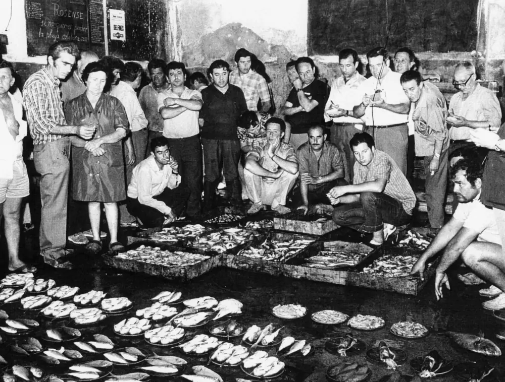 Fotografia antiga de pescadors al voltant de les caixes de peix a la llotja